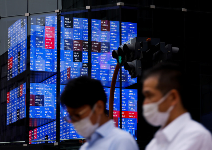Pessoas passam por uma tela eletrônica mostrando o índice de preços das ações Nikkei do Japão dentro de uma sala de conferências em Tóquio