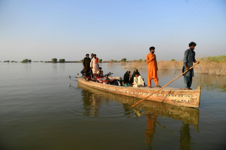 Deslocados internos usam um barco para atravessar uma área inundada em Dadu, na província de Sindh, no Paquistão, em 27 de outubro de 2022.