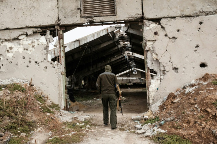 Um soldado ucraniano entra em um prédio destruído em uma granja industrial, perto da qual as forças russas foram escavadas