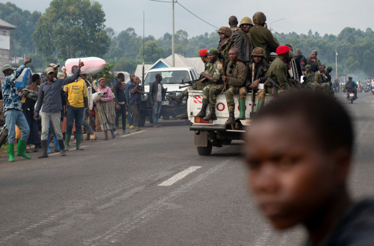 Membros das Forças Armadas da República Democrática do Congo (FARDC) patrulham perto de civis deslocados internamente que fogem de tensões renovadas de Kanyaruchinya para Goma