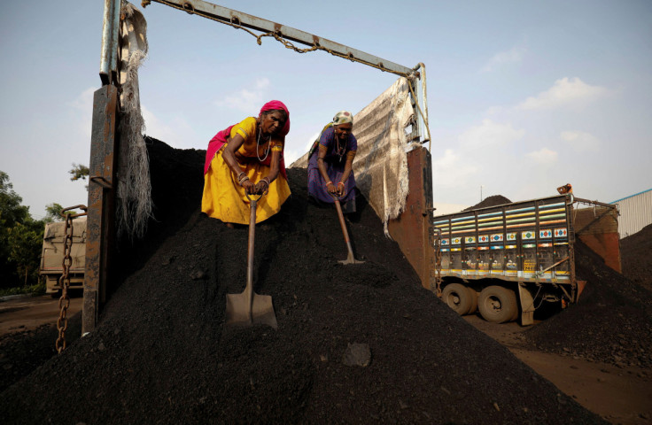 Trabalhadores descarregam carvão de um caminhão de abastecimento em um pátio nos arredores de Ahmedabad