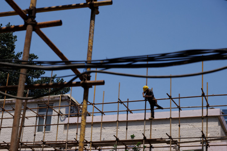 Um trabalhador aperta uma junta de andaime em um canteiro de obras de um prédio de apartamentos em reforma em Pequim