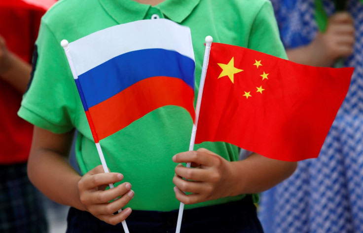 Uma criança segura bandeiras nacionais da Rússia e da China antes de uma cerimônia de boas-vindas ao presidente russo, Vladimir Putin, do lado de fora do Grande Salão do Povo em Pequim