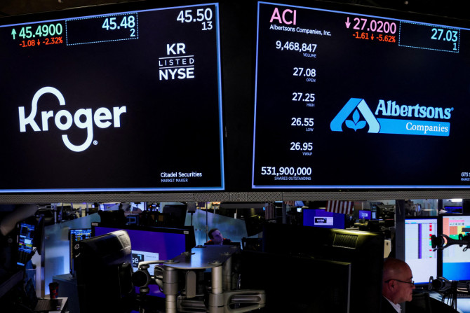 Os comerciantes trabalham como telas que exibem as informações de negociação para Kroger e Albertsons no pregão da NYSE em Nova York