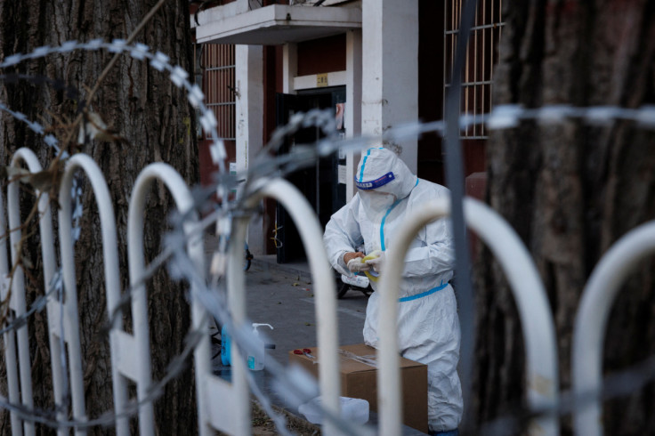 Um trabalhador de controle de pandemia em um traje de proteção trabalha em um complexo residencial parcialmente fechado enquanto os surtos da doença de coronavírus (COVID-19) continuam em Pequim