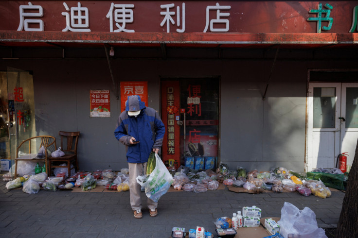 Um homem escolhe suas compras de supermercado em uma rua enquanto muitas lojas permanecem fechadas por causa da doença de coronavírus (COVID-19) em Pequim