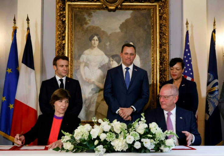 O presidente francês Emmanuel Macron (à esquerda) observa enquanto a ministra das Relações Exteriores da França, Catherine Colonna, e o governador da Louisiana, John Bel Edwards (canto inferior direito) assinam um acordo de energia limpa em Nova Orleans e