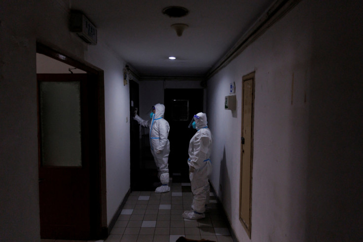 Trabalhadores de prevenção de pandemia em trajes de proteção batem na porta de um morador em um prédio de apartamentos que foi fechado enquanto os surtos de doença por coronavírus (COVID-19) continuam em Pequim