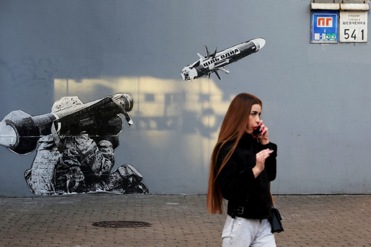 Uma mulher caminha pela parede pintada de grafite do lado de fora de uma cafeteria em Kiev