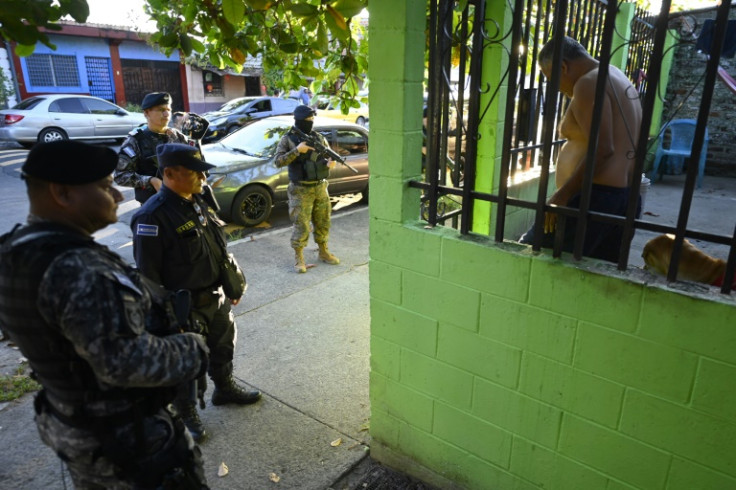 Soldados e policiais revistam uma casa em busca de membros de gangues durante uma operação em Soyapango