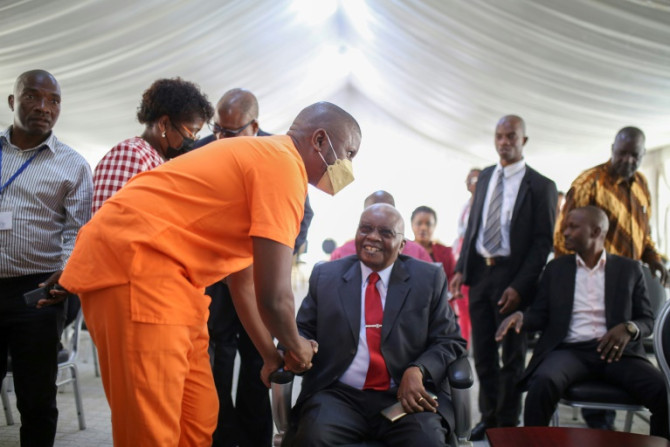 O ex-presidente Armando Guebuza, sentado, cumprimenta o filho Ndambi, arguido, na sessão de 30 de novembro em que começaram a ser lidas as sentenças