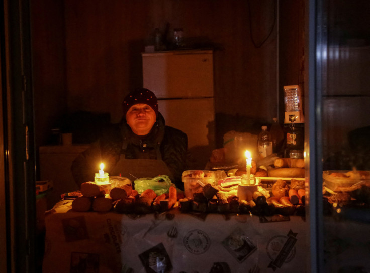 Um vendedor espera por clientes em uma pequena loja, iluminada com velas durante uma queda de energia, depois que a infraestrutura civil crítica foi atingida por ataques de mísseis russos em Odesa