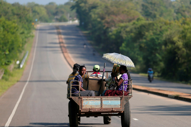 Aldeões viajam em um trator em uma estrada recém-construída em Hambantota