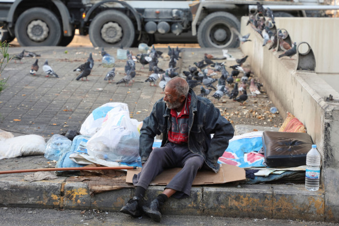 Um morador de rua senta em uma calçada ao longo de uma rua, em Beirute