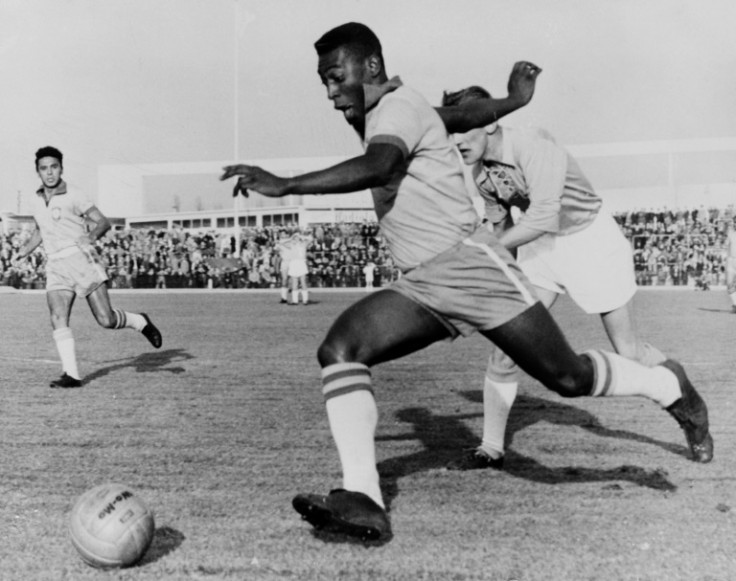 Nesta foto tirada em 8 de maio de 1960, a lenda do futebol brasileiro Pelé dribla um zagueiro durante um amistoso entre Malmo e Brasil, na Suécia