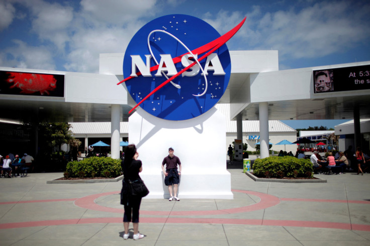 Turistas tiram fotos de uma placa da NASA no complexo de visitantes do Centro Espacial Kennedy em Cabo Canaveral, Flórida