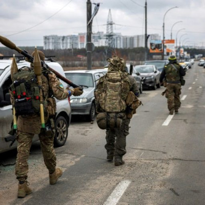 Militares ucranianos carregam granadas propelidas por foguetes e rifles de precisão enquanto caminham em direção à cidade de Irpin, a noroeste de Kyiv, em 13 de março de 2022