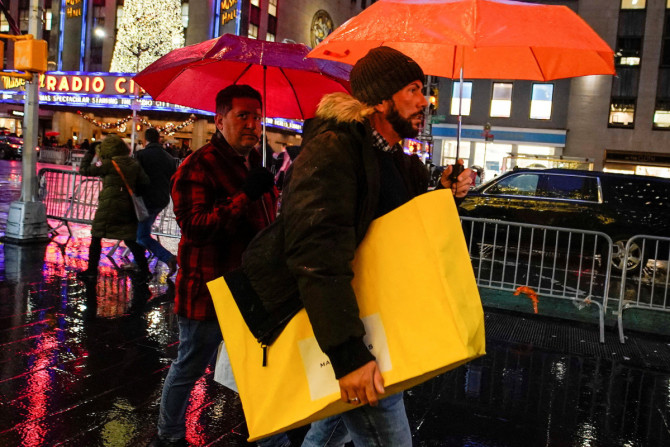 Um homem caminha sob a chuva com sua sacola de compras durante as festas de fim de ano em Nova York
