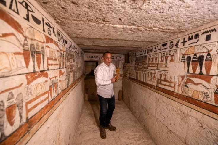 Mostafa Waziri, chefe do Conselho Supremo de Antiguidades do Egito, segura uma pequena estatueta em 19 de março de 2022, dentro de uma das cinco antigas tumbas faraônicas recentemente descobertas no sítio arqueológico de Saqqara, ao sul da capital Cairo