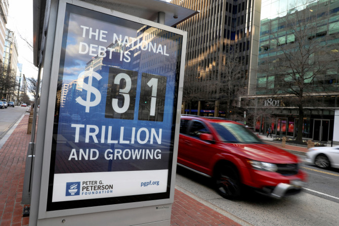 Carro passa ao lado de uma placa em um ponto de ônibus mostrando o valor da dívida nacional dos EUA em Washington
