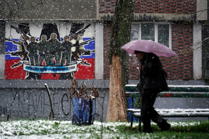 Um pedestre passa por um mural desfigurado para o mercenário Wagner Group da Rússia em Belgrado em 20 de janeiro de 2023