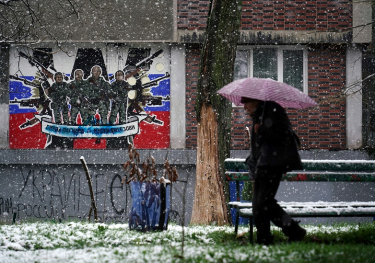 Um pedestre passa por um mural desfigurado para o mercenário Wagner Group da Rússia em Belgrado em 20 de janeiro de 2023