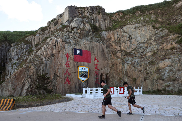 Soldados passam por um sinal da bandeira de Taiwan na ilha de Dongyin