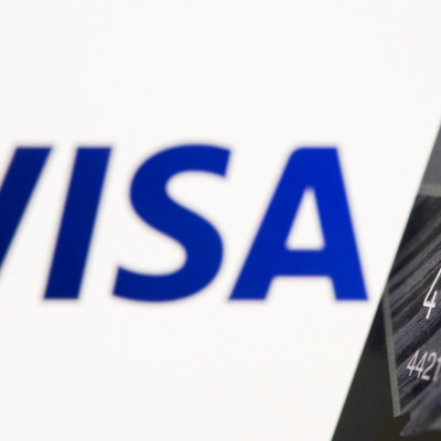 O cartão de crédito é visto na frente do logotipo da Visa exibido nesta ilustração