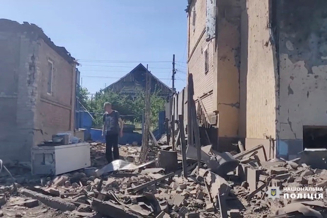 Um homem caminha sobre os escombros perto de prédios danificados, enquanto a invasão russa da Ucrânia continua, em Bakhmut