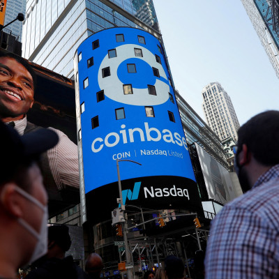 As pessoas assistem enquanto o logotipo da Coinbase Global Inc, a maior bolsa de criptomoedas dos EUA, é exibido no jumbotron Nasdaq MarketSite na Times Square em Nova York