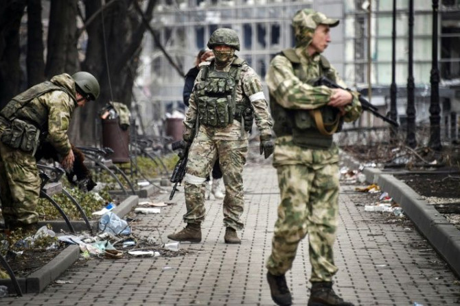 Soldados russos patrulham uma rua em Mariupol em 12 de abril de 2022, enquanto Moscou intensifica uma campanha para tomar a estratégica cidade portuária ucraniana