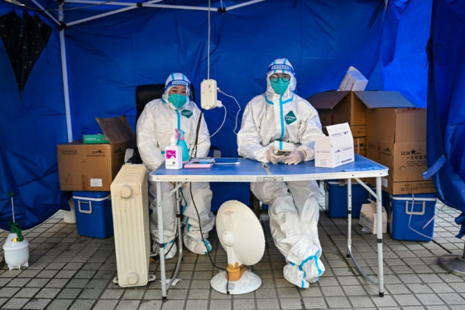 Profissionais de saúde esperam que as pessoas escaneiem um código de saúde para testar o coronavírus Covid-19 no distrito de Jing&#39;an, em Xangai, em 22 de dezembro de 2022.