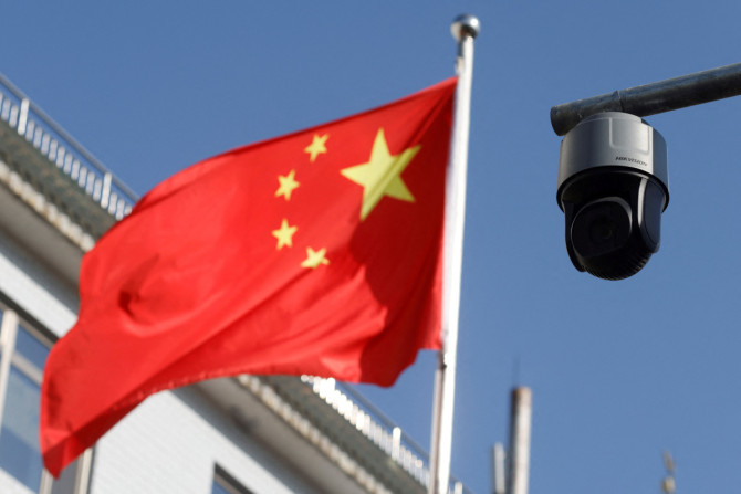 Uma câmera de vigilância de segurança com vista para uma rua é retratada ao lado de uma bandeira tremulante da China em Pequim
