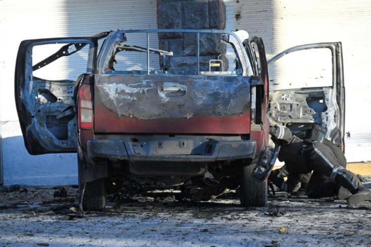 Polícia inspeciona os destroços de um carro queimado em frente à sede do SNAI em Quito